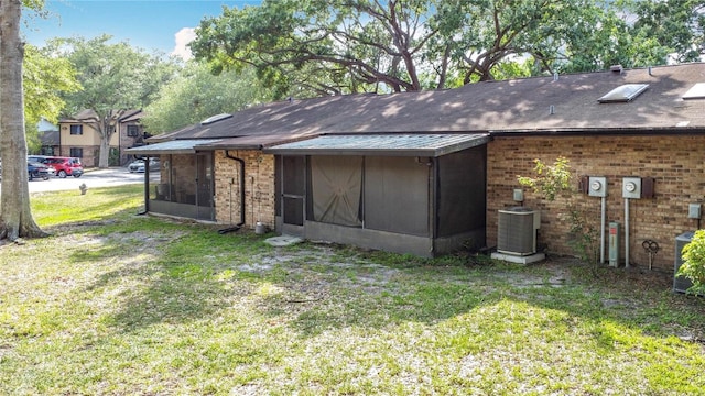 1803 Foxhall Cir Unit 1803, Kissimmee, FL 34741 - back of property with a sunroom, a lawn, central air condition unit, and brick siding