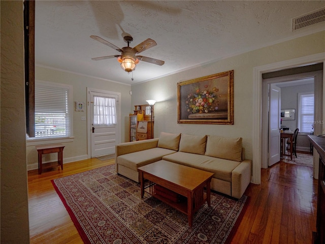 living area featuring crown molding, wood finished floors, a ceiling fan, a textured ceiling, and baseboards