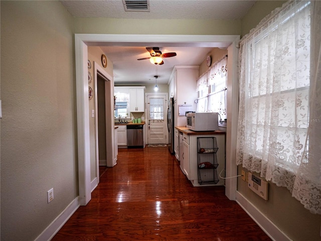 hallway featuring dark wood-type flooring, baseboards, and a sink