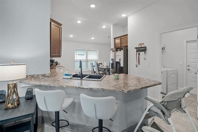503 Meadow Pointe Dr, Haines City, FL 33844 - kitchen with stainless steel fridge with ice dispenser, washer and dryer, a breakfast bar, a sink, and recessed lighting
