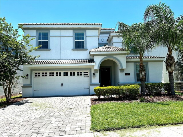1513 Maidstone Ct, Davenport, FL 33896 - mediterranean / spanish-style home with stucco siding, a tiled roof, decorative driveway, and an attached garage