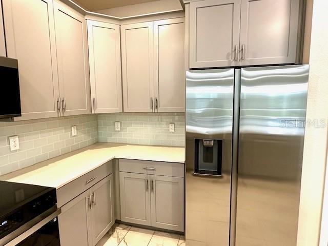 1513 Maidstone Ct, Davenport, FL 33896 - kitchen with stainless steel fridge, light countertops, gray cabinetry, decorative backsplash, and range with electric cooktop