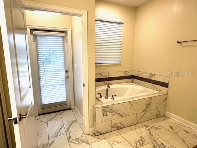 1513 Maidstone Ct, Davenport, FL 33896 - bathroom with marble finish flooring, baseboards, a garden tub, and plenty of natural light