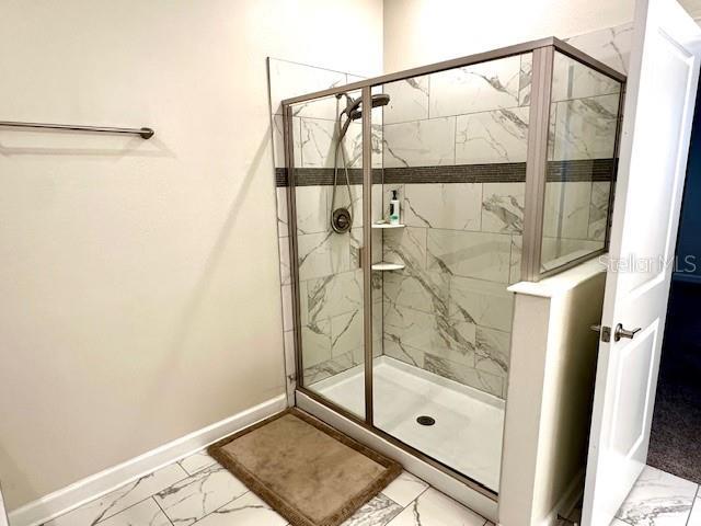 1513 Maidstone Ct, Davenport, FL 33896 - full bath featuring marble look tile flooring, a marble finish shower, and baseboards