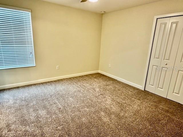 1513 Maidstone Ct, Davenport, FL 33896 - unfurnished bedroom with baseboards, carpet, a closet, ceiling fan, and multiple windows