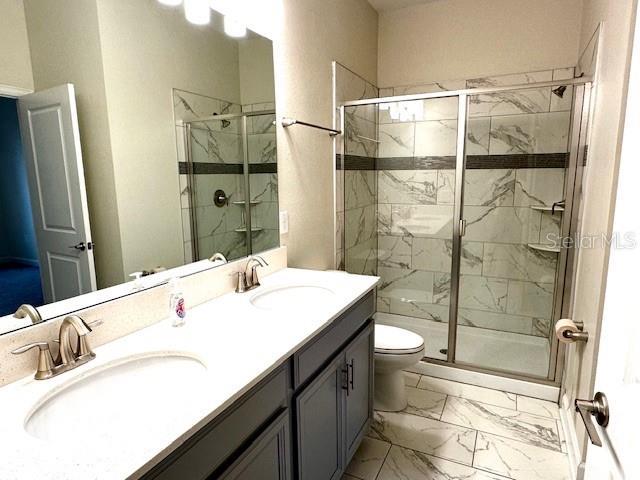 1513 Maidstone Ct, Davenport, FL 33896 - bathroom with marble finish floors, a stall shower, toilet, and double vanity