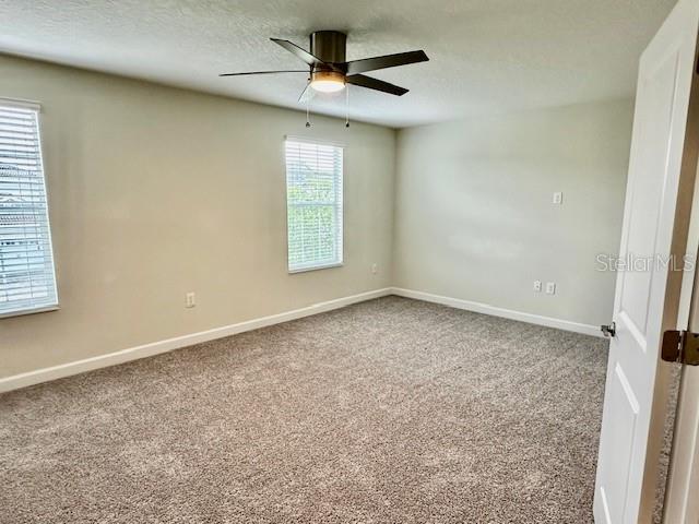 1513 Maidstone Ct, Davenport, FL 33896 - spare room featuring a ceiling fan, carpet floors, baseboards, and a textured ceiling