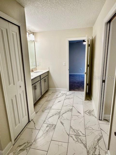 1513 Maidstone Ct, Davenport, FL 33896 - bathroom with baseboards, vanity, marble finish flooring, and a textured ceiling