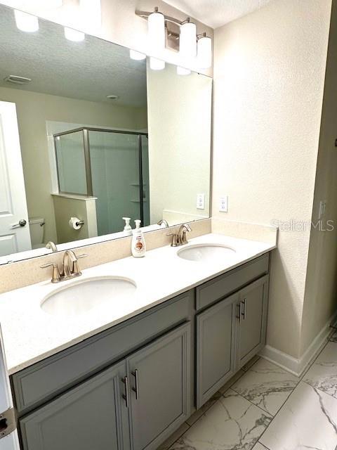 1513 Maidstone Ct, Davenport, FL 33896 - full bath with a shower stall, marble finish floors, toilet, double vanity, and baseboards