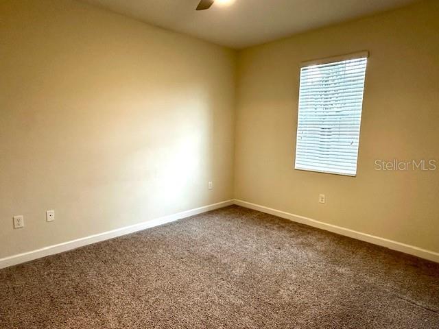 1513 Maidstone Ct, Davenport, FL 33896 - empty room with a ceiling fan, dark carpet, and baseboards