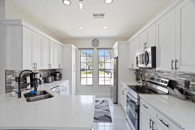 166 Minniehaha Cir, Haines City, FL 33844 - kitchen featuring stainless steel appliances, a sink, tasteful backsplash, light countertops, and recessed lighting