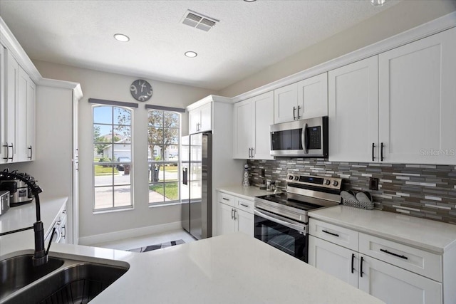 166 Minniehaha Cir, Haines City, FL 33844 - kitchen featuring appliances with stainless steel finishes, backsplash, recessed lighting, white cabinets, and light countertops