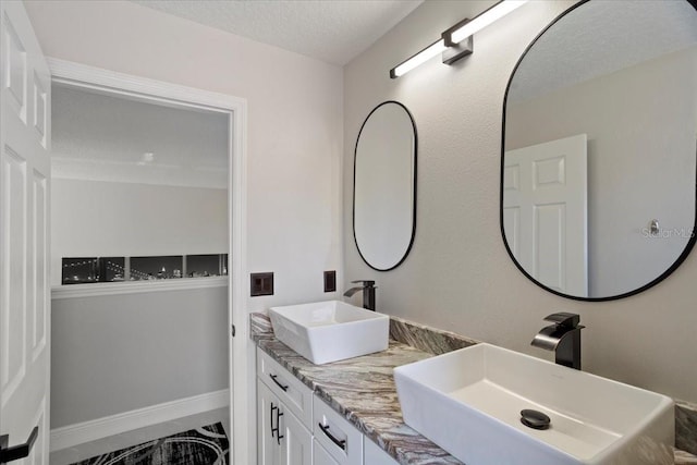 166 Minniehaha Cir, Haines City, FL 33844 - bathroom featuring double vanity, a textured ceiling, marble finish floors, and baseboards
