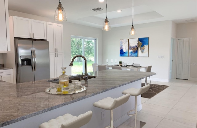 kitchen with stainless steel refrigerator with ice dispenser, stone countertops, a sink, a breakfast bar, and recessed lighting