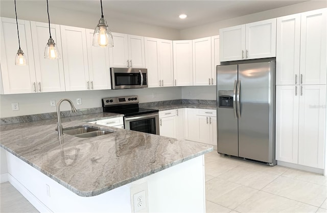 kitchen with appliances with stainless steel finishes, a sink, a peninsula, light stone counters, and white cabinetry