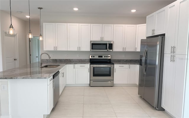 kitchen with stainless steel appliances, a sink, a peninsula, stone countertops, and white cabinetry