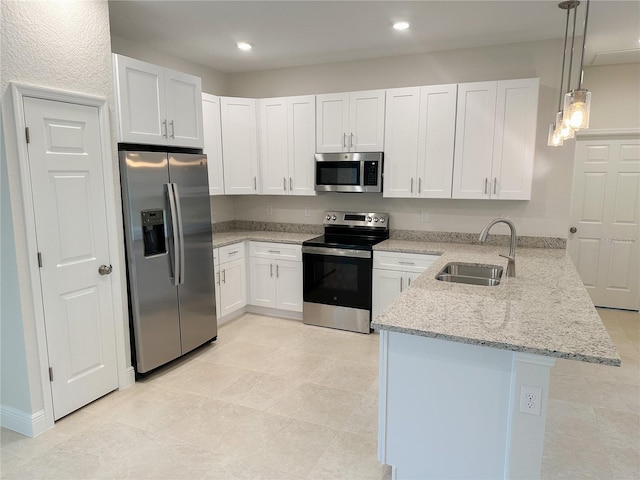 kitchen featuring stainless steel appliances, a sink, a peninsula, light stone countertops, and white cabinetry