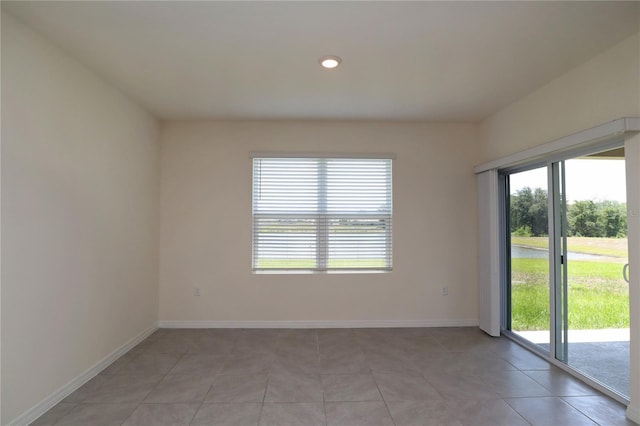 empty room featuring healthy amount of natural light, light tile patterned floors, baseboards, and recessed lighting