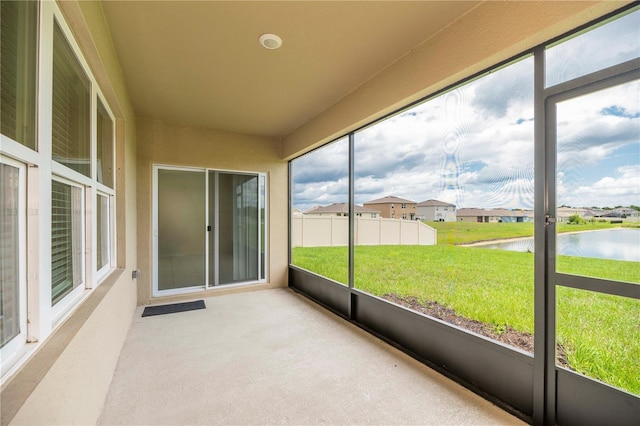 unfurnished sunroom featuring a water view and a residential view