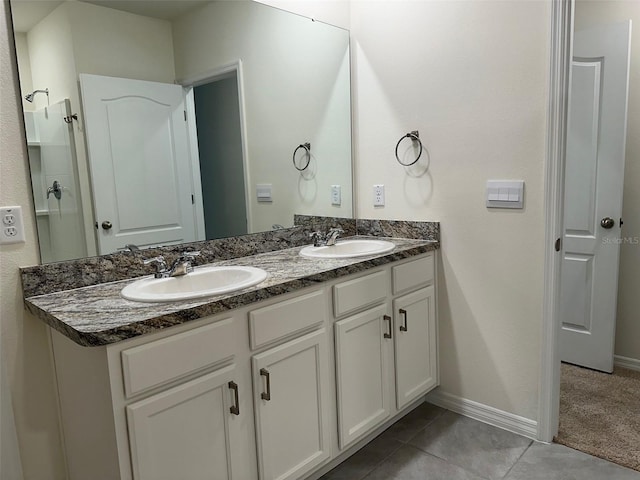 bathroom with double vanity, baseboards, and tile patterned flooring