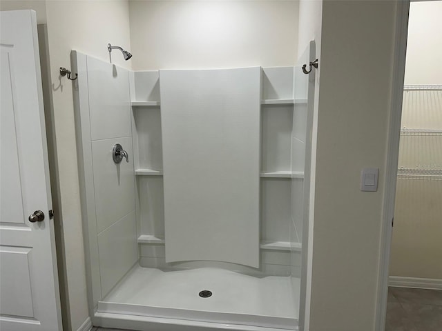 bathroom with a shower stall, baseboards, and tile patterned flooring