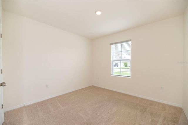 empty room featuring light colored carpet, baseboards, and recessed lighting