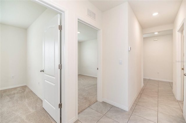 hallway featuring recessed lighting, light tile patterned flooring, baseboards, and light colored carpet