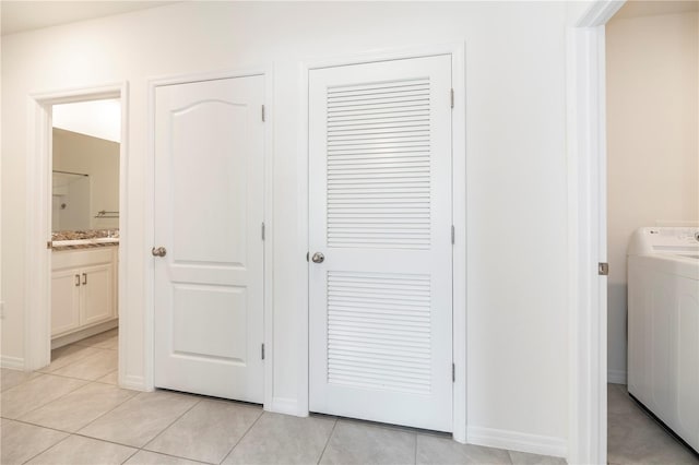 corridor with washer / clothes dryer and light tile patterned floors
