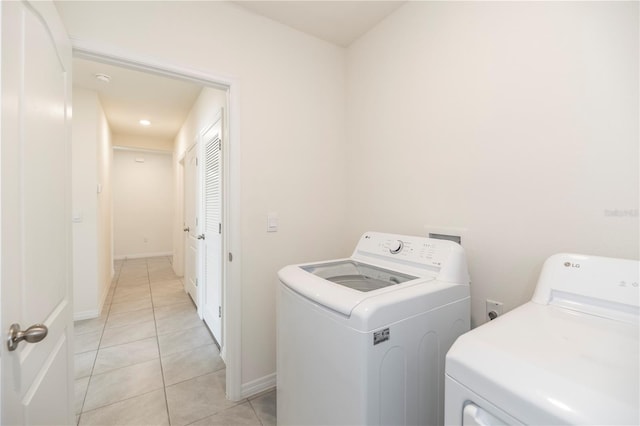 laundry room with washing machine and dryer, light tile patterned floors, and baseboards