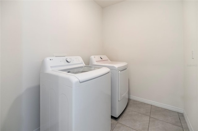 laundry area with washing machine and clothes dryer, baseboards, and light tile patterned floors