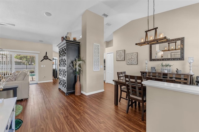 dining room featuring dark wood-type flooring, baseboards, and high vaulted ceiling