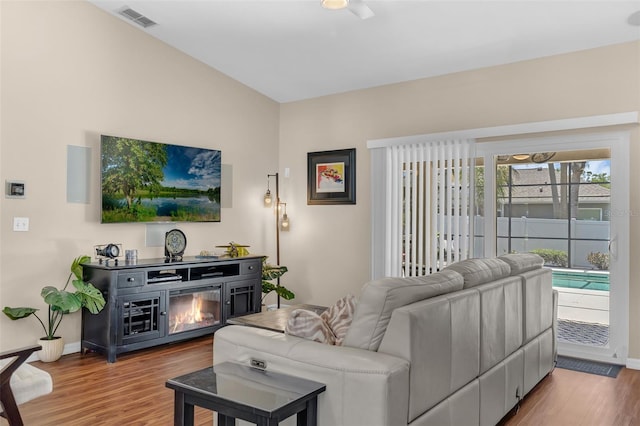 living room featuring wood finished floors, baseboards, and a glass covered fireplace