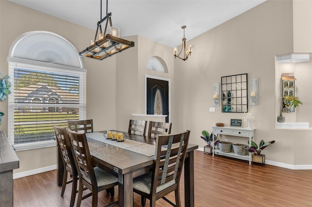 dining room with a chandelier, wood finished floors, baseboards, and a high ceiling