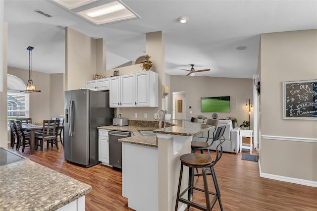kitchen featuring appliances with stainless steel finishes, a sink, a kitchen breakfast bar, lofted ceiling, and open floor plan
