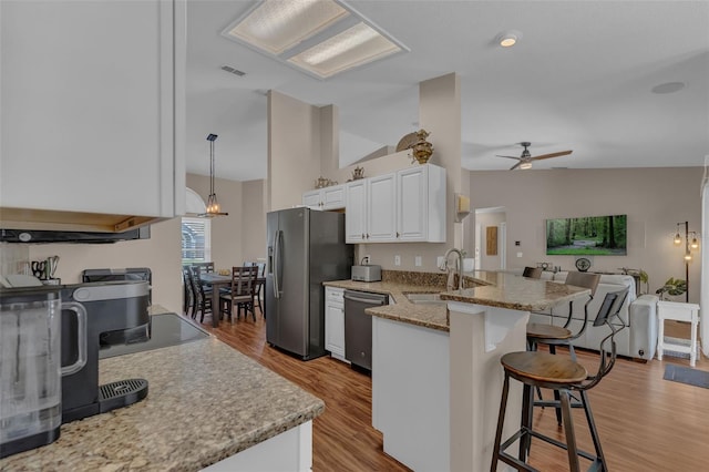 kitchen with appliances with stainless steel finishes, a breakfast bar, a sink, ceiling fan, and a peninsula
