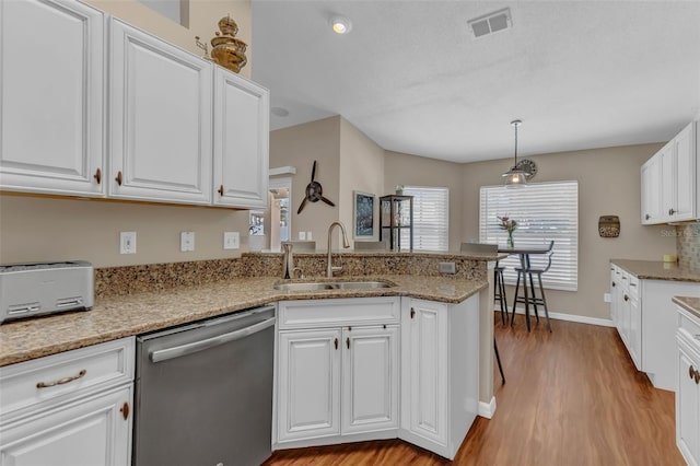 kitchen with stainless steel dishwasher, a sink, light wood-style floors, and white cabinets