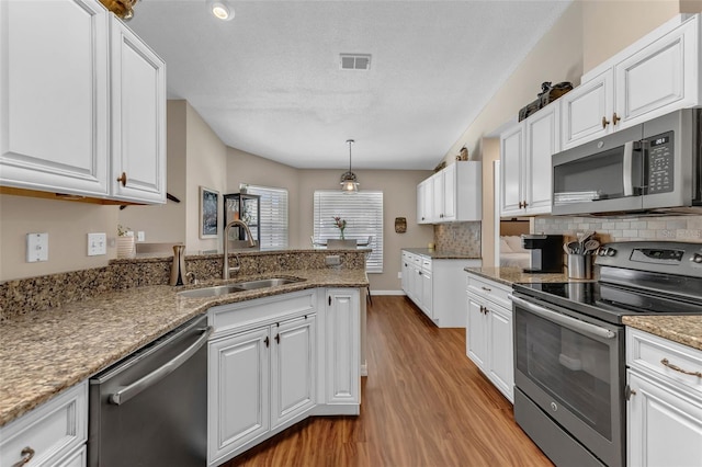 kitchen featuring stainless steel appliances, a sink, light wood-style floors, and white cabinets