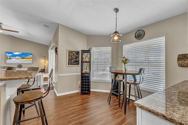 dining area featuring wood finished floors, baseboards, a ceiling fan, and lofted ceiling
