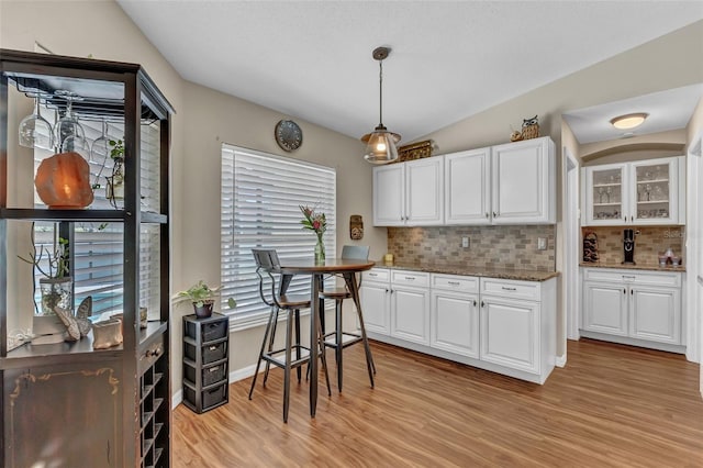 kitchen with plenty of natural light, backsplash, light wood-style flooring, and white cabinetry