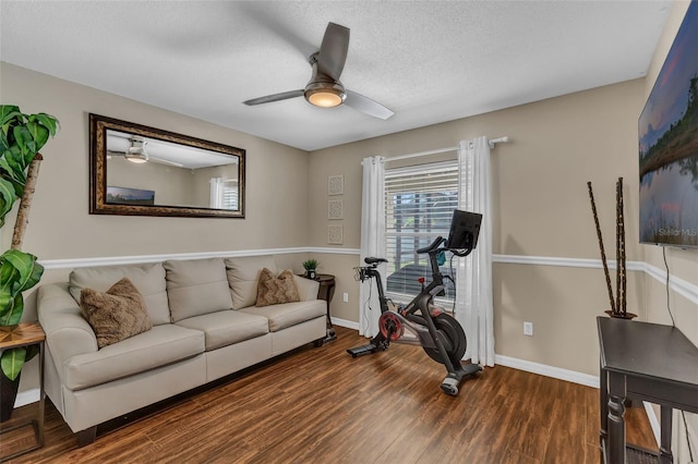 exercise area with a ceiling fan, wood finished floors, baseboards, and a textured ceiling