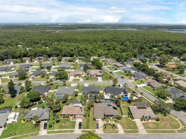 aerial view of property's location featuring a forest, nearby suburban area, and a large body of water