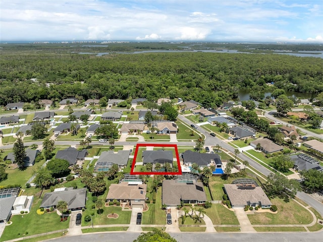 aerial overview of property's location featuring a heavily wooded area, property boundaries highlighted, a large body of water, and nearby suburban area