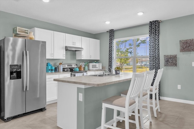 1555 Dawnview Way, Kissimmee, FL 34744 - kitchen featuring appliances with stainless steel finishes, under cabinet range hood, white cabinetry, a breakfast bar area, and recessed lighting