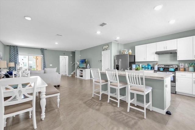 1555 Dawnview Way, Kissimmee, FL 34744 - kitchen with stainless steel appliances, under cabinet range hood, open floor plan, a kitchen island with sink, and light countertops