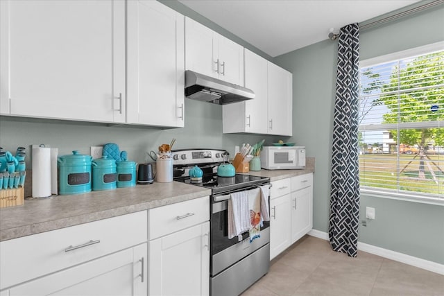 1555 Dawnview Way, Kissimmee, FL 34744 - kitchen featuring electric range, under cabinet range hood, white microwave, light countertops, and healthy amount of natural light