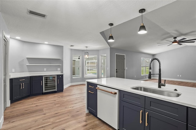 1438 Mclin Dr, Plant City, FL 33565 - kitchen featuring beverage cooler, a sink, dishwasher, light wood-type flooring, and a textured ceiling