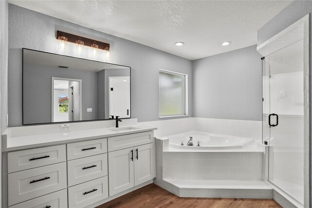 1438 Mclin Dr, Plant City, FL 33565 - bathroom with a textured ceiling, plenty of natural light, a garden tub, wood finished floors, and a stall shower