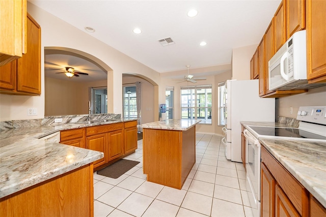 7263 Winding Lake Cir, Oviedo, FL 32765 - kitchen featuring white appliances, a ceiling fan, a sink, brown cabinetry, and light stone countertops