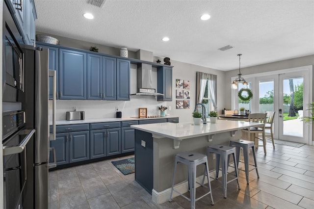 3865 W Stillwood Ln, Lake Mary, FL 32746 - kitchen with blue cabinetry, wall chimney range hood, a breakfast bar area, light countertops, and a textured ceiling