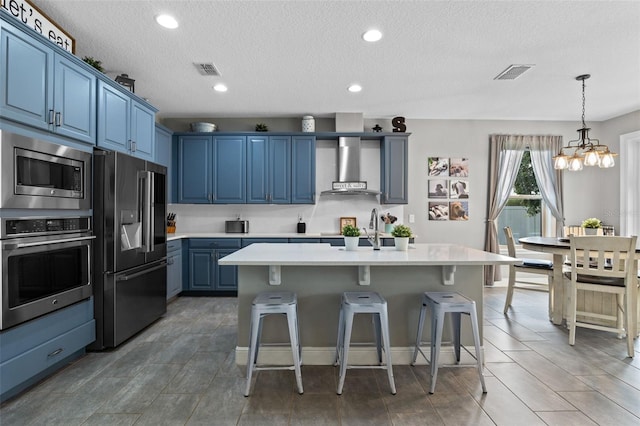 3865 W Stillwood Ln, Lake Mary, FL 32746 - kitchen with appliances with stainless steel finishes, wall chimney exhaust hood, blue cabinets, light countertops, and a chandelier